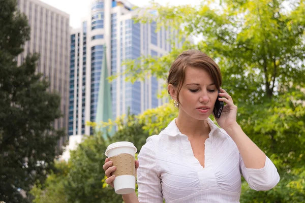 Γυναίκα με καφέ στο αστικό πάρκο χρησιμοποιώντας έξυπνο τηλέφωνο — Φωτογραφία Αρχείου