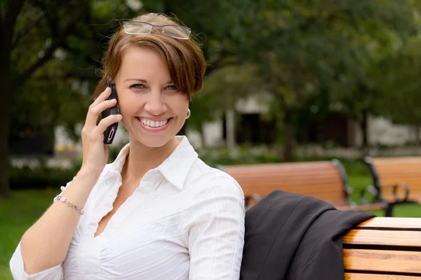 Attraktiv kvinna samtal på mobiltelefonen i parken — Stockfoto