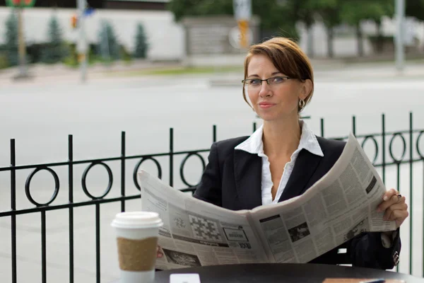 Mujer de negocios lee el periódico mientras toma café —  Fotos de Stock