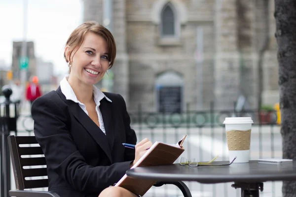 Sorridente donna d'affari scrive note al caffè — Foto Stock