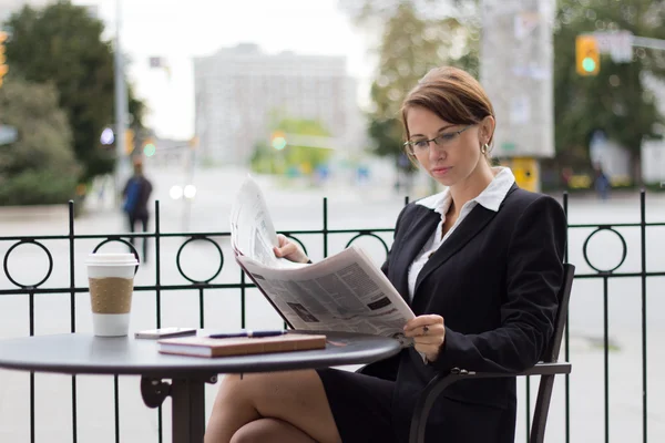 Atractiva mujer de negocios lee el periódico en la cafetería al aire libre —  Fotos de Stock