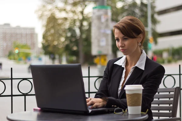 Business woman working on laptop at outdoor cafe — Stock Photo, Image
