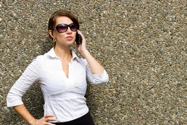 Mujer sofisticada con gafas de sol usando teléfono inteligente móvil — Foto de Stock