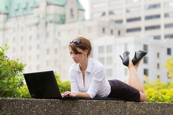 La donna d'affari giovane casualy lavora su computer portatile nella città — Foto Stock