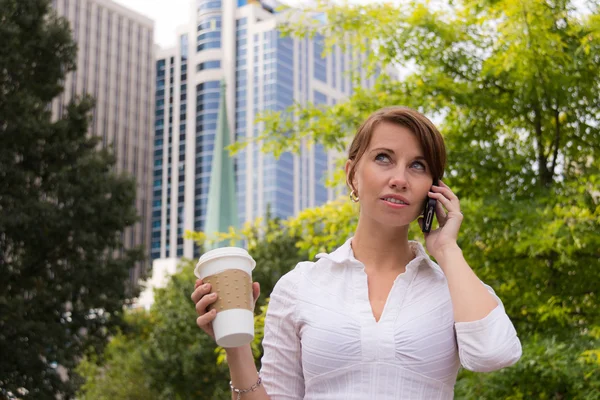 Kvinna med kaffe i stadsparken med smart telefon — Stockfoto