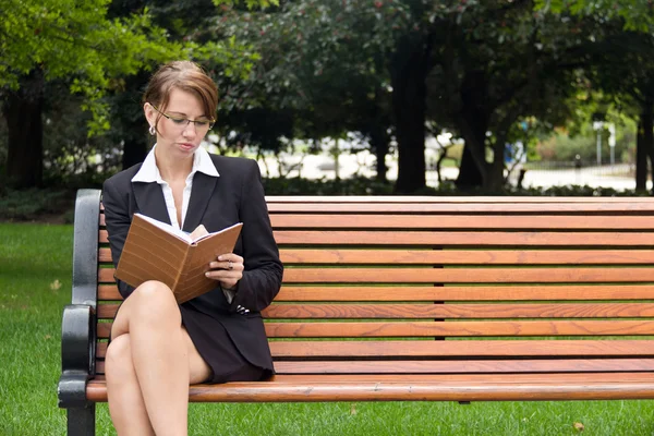 Stylish business woman siting on park bench writing in notebook — Stock Photo, Image