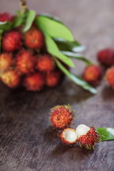 A brunch of r ambutans with leaves and peel on a wooden table in Vietnam — Stock Photo, Image