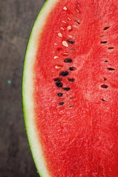 Eine Hälfte Wassermelone auf einem dunklen Tisch — Stockfoto