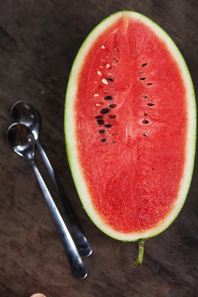 La mitad de la sandía y la cuchara sobre la mesa — Foto de Stock