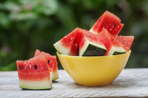 Wassermelonenstücke in einem gelben Teller auf einem weißen Holztisch — Stockfoto