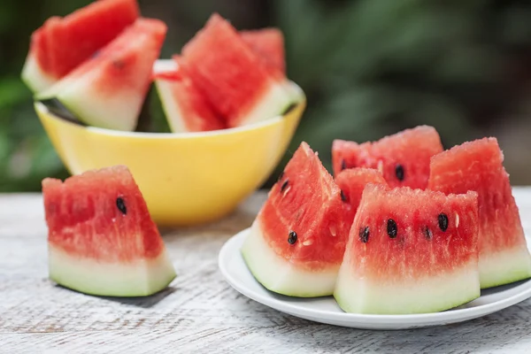 Wassermelonenstücke in zwei Tellern auf einem weißen Holztisch — Stockfoto