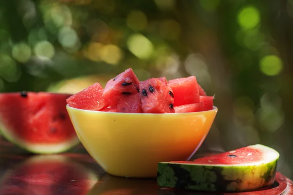 Vandmelon stykker i en gul plade og skiver på et hvidt træ - Stock-foto