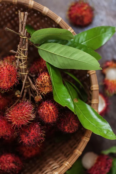 Rambutans and leaves  in a wicker basket — Stock Photo, Image