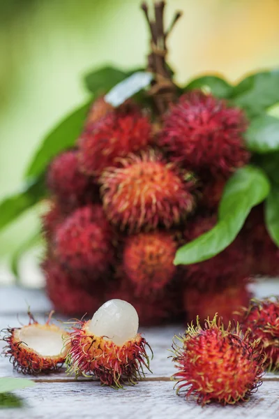 红毛丹水果和树叶堆在桌子上 — 图库照片