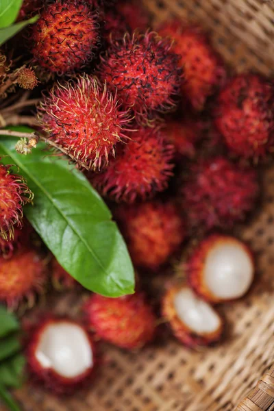 Rambutans and leaves  in a wicker basket — Stock Photo, Image