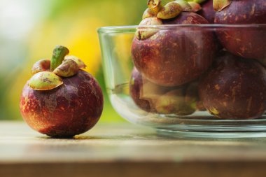 bir cam kase ve bir masanın üzerine mangosteens