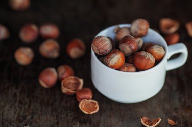karanlık bir tablo üzerinde beyaz bir fincan fındık