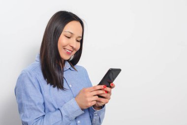 Akıllı telefon kullanan genç bir kadın. Beyaz bir arkaplanda.