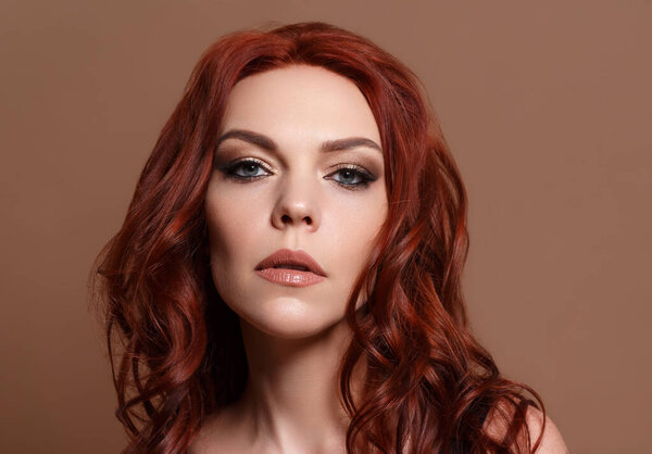 Beauty portrait of a red-haired beautiful woman on a beige background..