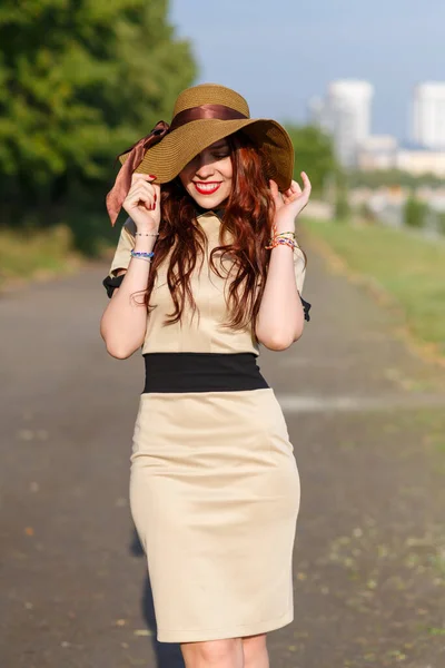 一个戴着宽礼帽的快乐的年轻女子在公园里摆姿势 — 图库照片