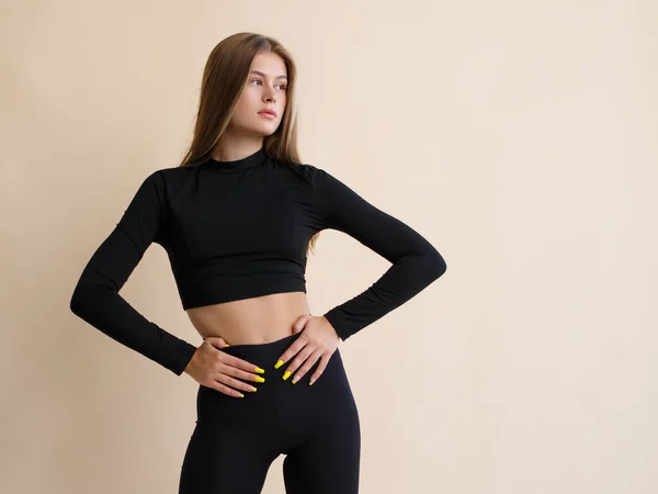 Portret Van Een Slanke Jonge Fitnessvrouw Zwarte Sportkleding Een Beige — Stockfoto