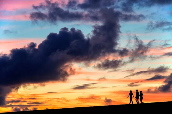 スペインのプエルト クルスの夕日を歩く3人の女の子のシルエット — ストック写真