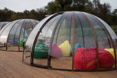 Ahşap bir terasta şeffaf bir Igloo. Farklı şirketler için izole edilmiş bir yer. Koronavirüsten korunma.