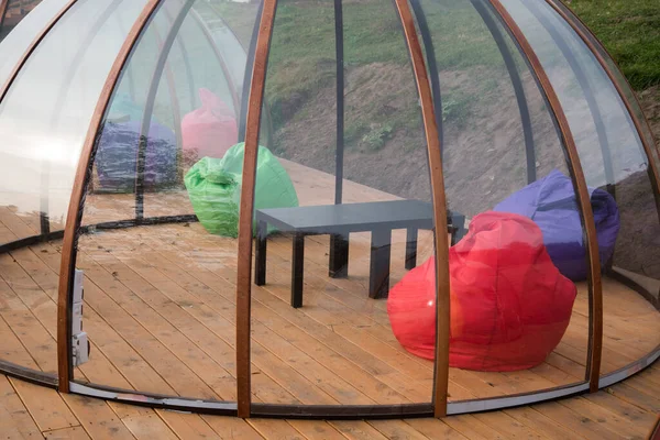 Transparent Igloo on a wooden terrace. Isolated premises for different companies. Protection from coronavirus.