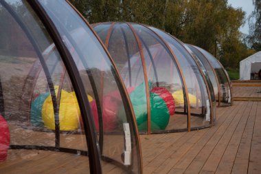 Ahşap bir terasta şeffaf bir Igloo. Farklı şirketler için izole edilmiş bir yer. Koronavirüsten korunma.
