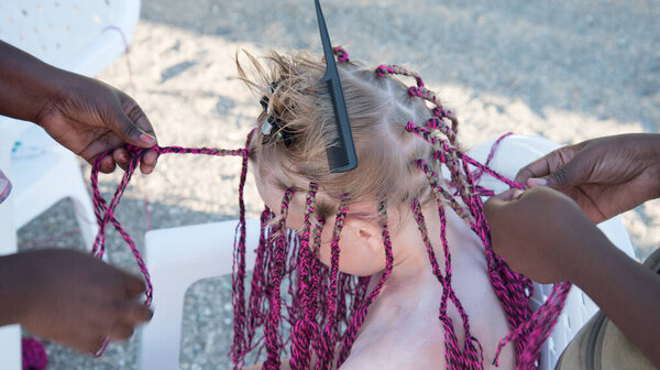 The process of weaving African braids. Girls braid African-American braids. Fashion and beauty.