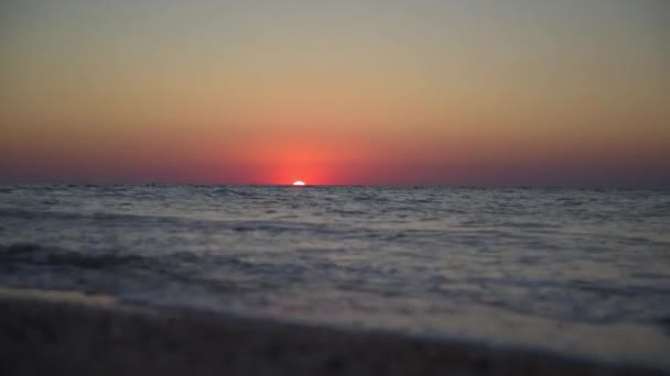 Spokojny obraz morskiego zachodu słońca. Czerwone słońce zachodzi w morzu. Nadchodzą fale. Niebo jest kolorowe. — Wideo stockowe