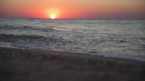 Spokojny obraz morskiego zachodu słońca. Czerwone słońce zachodzi w morzu. Nadchodzą fale. Niebo jest kolorowe. — Wideo stockowe