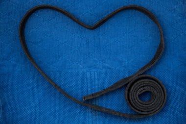 Yukarıdan manzara. Kemer bir kalp şeklinde katlanır. Judo aşkı. Judo dersleri için kimono ve siyah kuşak. Kimono mavi. Arkaplan, doku