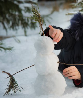 Bir çocuk kardan adam yapar. Keyfi yerindeyken, kız gülümser ve kardan adama elini uzatır..