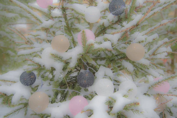 Neujahrshintergrund. Auf den schneebedeckten Fichtenpfoten befinden sich Kugelgirlanden. Weicher Fokus. — Stockfoto