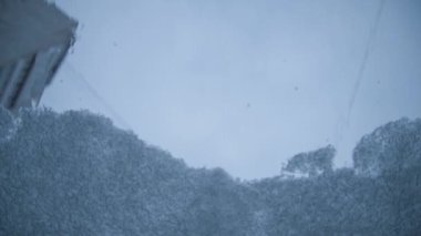 Arabanın ön camında kar eritme işlemi. Erimiş kar ve buz yavaş yavaş aşağı kayıyor. İçeriden. Isıtılmış cam.