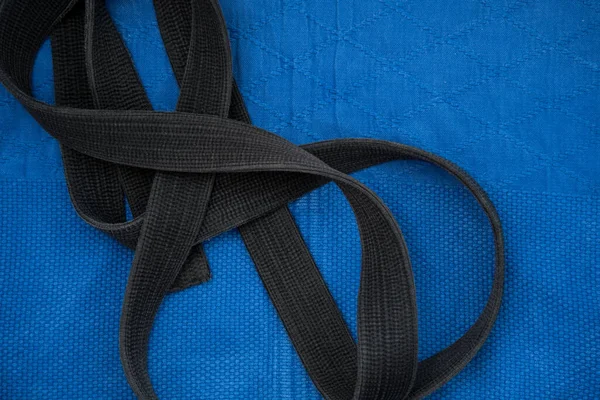 La vista desde arriba. Kimono para clases de judo y cinturón negro. El kimono es azul. Fondo, textura. — Foto de Stock