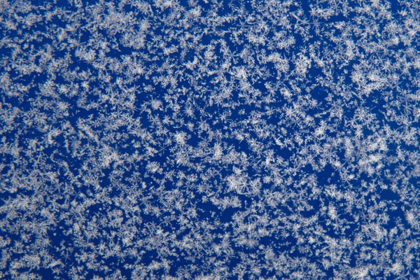 Il y a des flocons de neige blancs sur la surface bleue. Contexte, texture de la neige. Concentration douce — Photo