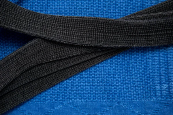 La vue du haut. Kimono pour des cours de judo et une ceinture noire. Le kimono est bleu. Contexte, texture. — Photo