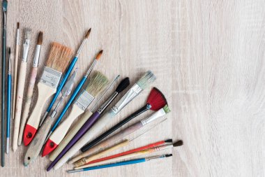 Çeşitli sanatçı fırçaları olan bir masanın üst görüntüsü. Mesaj için yer var. Yaratıcı bir kartpostal için arka plan, doku