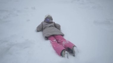 Okul çağındaki bir çocuk kar yığınlarında zevkle sürünür. Sert kış ve bol kar. Çocuk karda oynuyor.