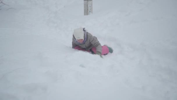 笑っている少女は雪の中で単に転倒する 冬の天気と陽気な気分 バラ色で幸せな子供 — ストック動画