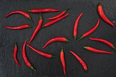 Kırmızı biberler siyah bir arka planda sergilenir. Metne yer var.