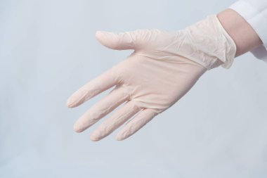 Doktorun eli tokalaşmak için uzatıldı. Eline koruyucu bir tıbbi eldiven takılır. Eldiven modu. Yakın plan. Virüs koruma kavramı