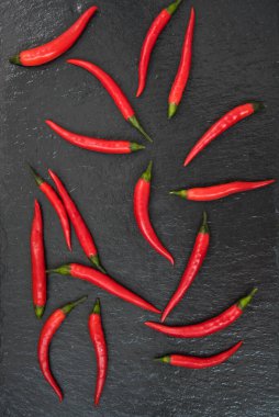 Kırmızı biberler siyah bir arka planda sergilenir. Metne yer var.