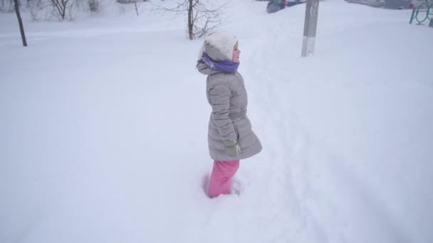 El niño yace en la nieve con placer y hace un ángel. Mucha nieve y heladas. Feliz infancia. — Vídeos de Stock