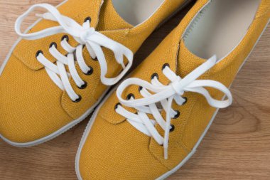 Doğal kumaştan yapılmış hardal renginde spor ayakkabılar. Yukarıdan bak. Beyaz arka plan. Parlak sulu renk, modern tarz. Metin için bir yer var
