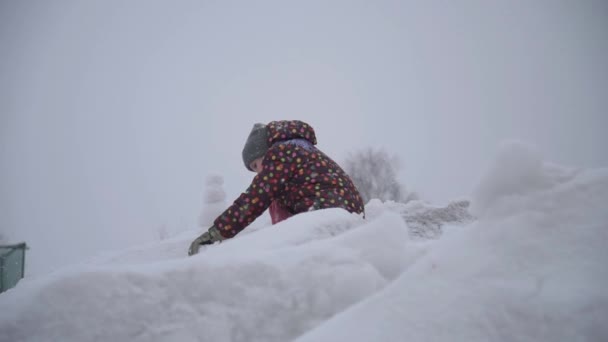 Dítě školního věku si hraje na vrcholu zasněžené hory. Zimní procházky a zábavní koncept. Dívka si hraje se sněhem — Stock video