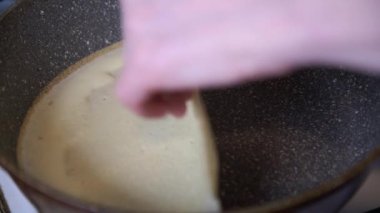 Yakın plan. Eller tavada krep çeviriyor. Krep her iki tarafta da pişiyor.