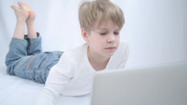 Sarışın çocuk bilgisayar veya dizüstü bilgisayar ekranına dikkatle bakar. Yakın plan portre